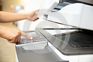 Close up hand office man press copy button on panel to using the copier or photocopier machine for scanning