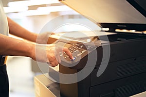 Close up hand office man press copy button on panel to using the copier or photocopier machine for scanning