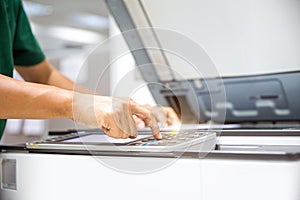 Close up hand office man press copy button on panel to using the copier or photocopy machine for scanning