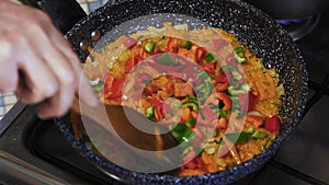Close-Up, Hand of an Older Woman Using a Wooden Shovel Stir Fry Vegetable Stews in a Pan