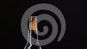 Close up of a hand opening a glass bottle. Video. Alcoholic drink isolated on black background, concept of party.