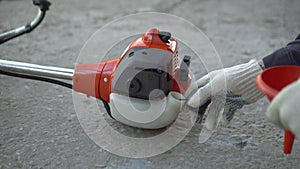 Close-up hand opens the gas tank cover on a lawn mower