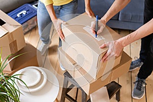 Close up of hand packing cardboard box, concept moving house. Young couple moving to a new apartment together