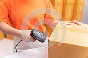 Close up hand of parcel delivery worker in warehouse with barcode scanner