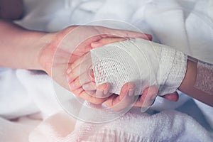 Close up hand of parent holding hand of child in hospital. Retro