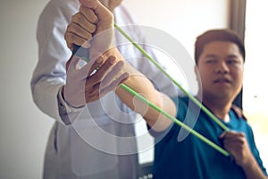 Close up hand patient doing stretching exercise with a flexible exercise band and a physical therapist hand to help in clinic room