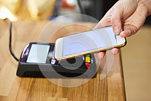 Close up hand paying order by credit card on payment terminal in the coffee shop