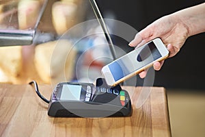 Close up hand paying order by credit card on payment terminal in the coffee shop