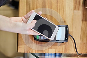 Close up hand paying order by credit card on payment terminal in the coffee shop