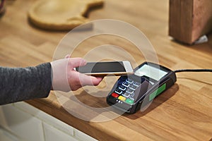 Close up hand paying order by credit card on payment terminal in the coffee shop