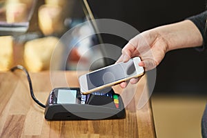 Close up hand paying order by credit card on payment terminal in the coffee shop