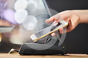 Close up hand paying order by credit card on payment terminal in the coffee shop