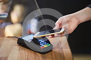 Close up hand paying order by credit card on payment terminal in the coffee shop