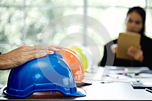 Close up hand placing on Blue Construction Safety Helmets on Office Table