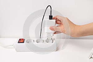 Close-up of hand plugging a plug into a multiple socket