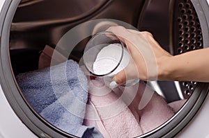 Close up of a hand pouring detergent into the washing machine