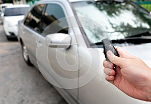 Close up hand press the remote control to unlock or lock car at garage or parking lot. Technology of automotive security system to photo