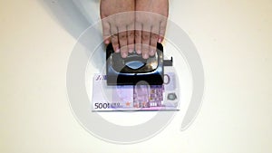 close - up, the hand presses the hole in which the bill is invested five hundred euros, money