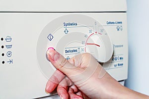 Close up hand presses start on washing machine