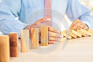 Close-up hand prevent wooden block not falling domino concepts of financial risk management and strategic planning and business