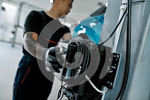 Close up of hand of professional male mechanic operating hydraulic lift, pushing button up at auto repair shop