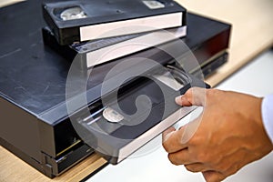 Close-up hand put or insert video cassette tape VHS old retro style on video record playback concept of vintage electric and elect