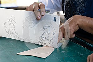 Close-up hand-raising tracing paper which is clear paper, with clear pattern on paper, compared to get same shape size as cut