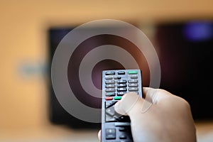 Close-up of hand with the remote control television and presses the button. Television remote control changes channels thumb on