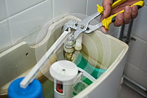 Close up of hand repairing toilet