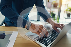 Close up. hand's business man wearing suit typing and working on laptop computer on wooden table at home office.