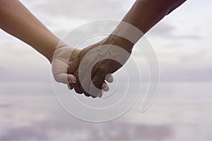 Close up hand of senior couple holding hand together near seaside at the beach,filtered image,light effect added,selective focus