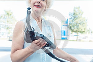 Close-up of the hand of a senior female driver holding the gas dispenser