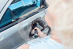 Close-up of the hand of a senior woman filling up the gas tank of her car