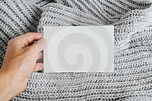 Close-up of hand showing white postcard mockup with blank space for text or bernding. Card template