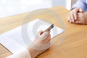 A close-up hand signs a document with a pen, a lease agreement, a contract.