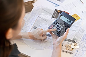 Close up hand of stress asian young businesswoman using calculator for calculate tax, expense of bills, credit card for payment on