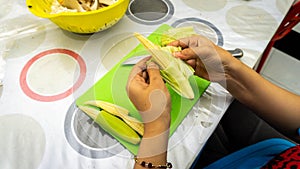 Close up hand taking out the baby corn cover to get the corn for cooking ingredients for making vegetable soup