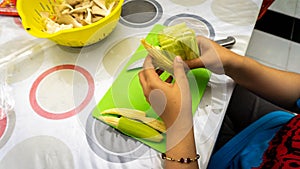 Close up hand taking out the baby corn cover to get the corn for cooking ingredients for making vegetable soup