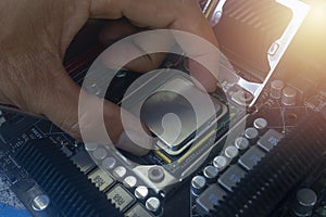 Close up hand of technician putting CPU on the socket of computer motherboard