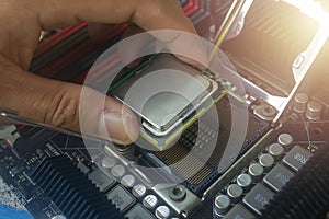 Close up hand of technician putting CPU on the socket of computer motherboard