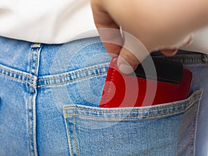 Close-up of a the hand of thief stealing the wallet to a woman.