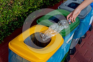 Close up hand throwing plastic bottle recycling container garbage sorting rubbish collection bin.