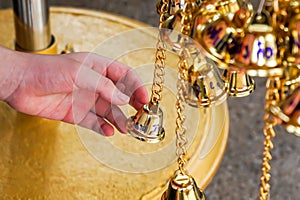 Close up hand touch small golden bells in Thai temple Non-English in an image is mean Wish in English