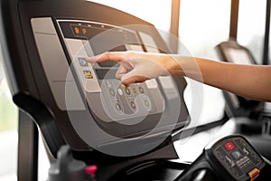 Close up hand turn on treadmill, finger pressing on button of running machine in gym