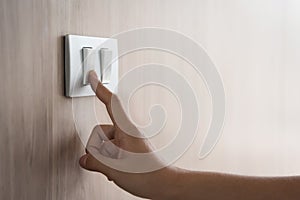 Close up hand turning on or off on grey light switch