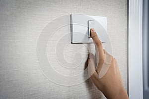 Close up hand turning on or off on grey light switch