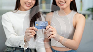 Close up hand of Two beautiful young women show their credit cards in the living room. The concept suggests inviting you to use