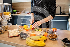 Close up on hand of unknown caucasian woman holding knife cutting kiwi and oranges copy space