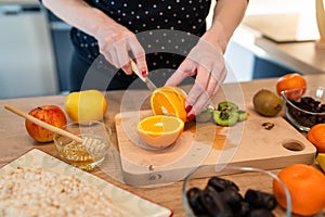 Close up on hand of unknown caucasian woman holding knife cutting kiwi and oranges copy space