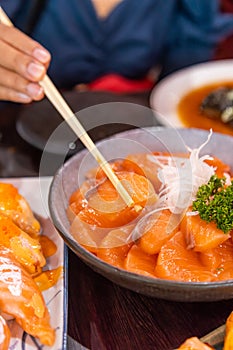 Close up Hand used Chopstick Picking Salmon Sashimi Japanese Food in Bowl